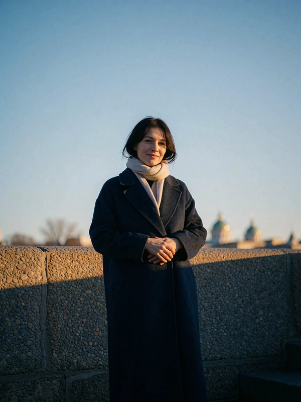 Dark-haired Russian woman in a charcoal wool coat on a river embankment in winter light
